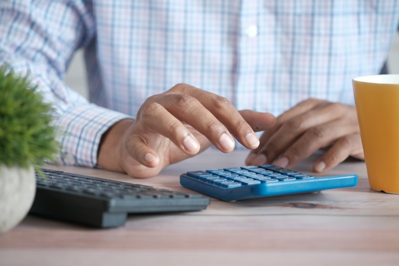 Mãos fazendo contas em uma calculadora sobre a mesa